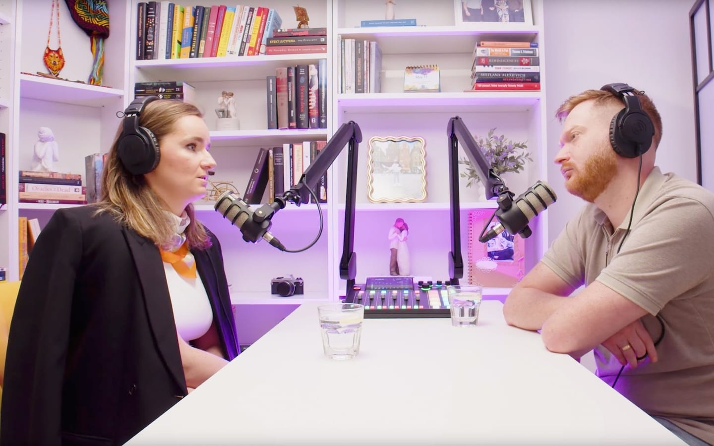 The Library: a bookcase behind a white desk set for two microphones